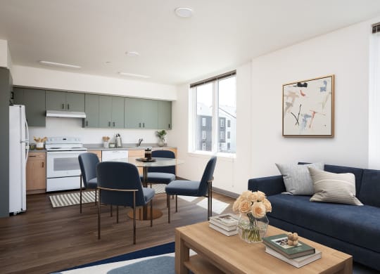 a living room with a blue couch and a kitchen with a table and chairs