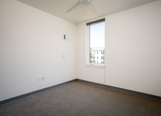 an empty room with a window and a ceiling fan