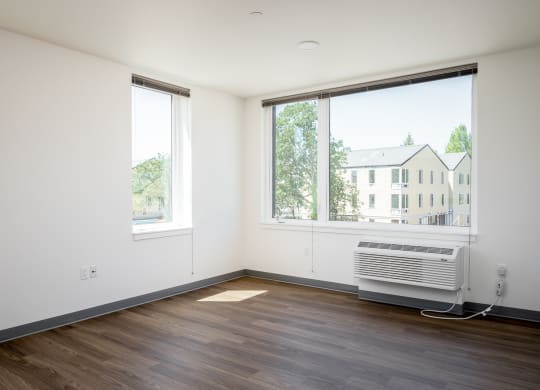an empty room with a radiator and two windows