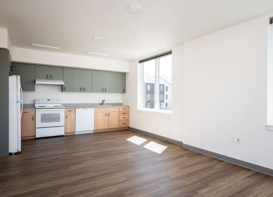 an empty kitchen with white appliances and wood flooring