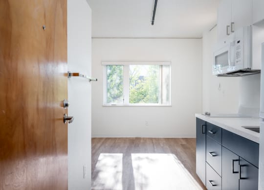 a kitchen with white walls and a wooden floor
