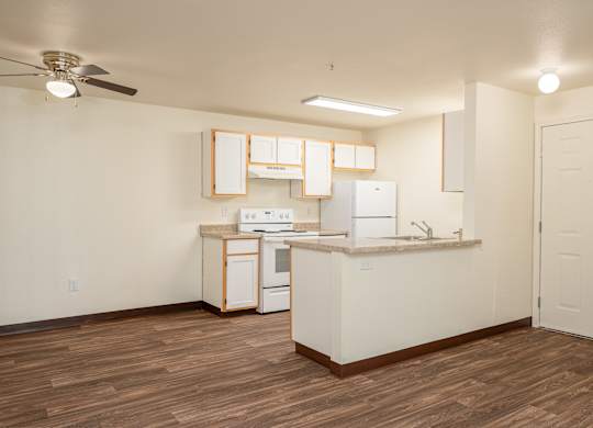 A kitchen with white cabinets and a wooden floor.