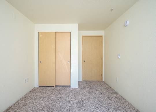 A room with two doors and carpeted floor.