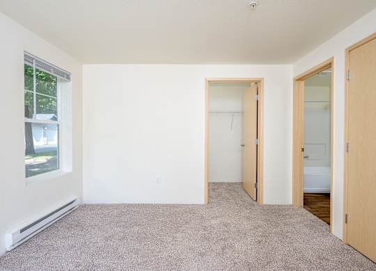 A room with a carpeted floor and a window.