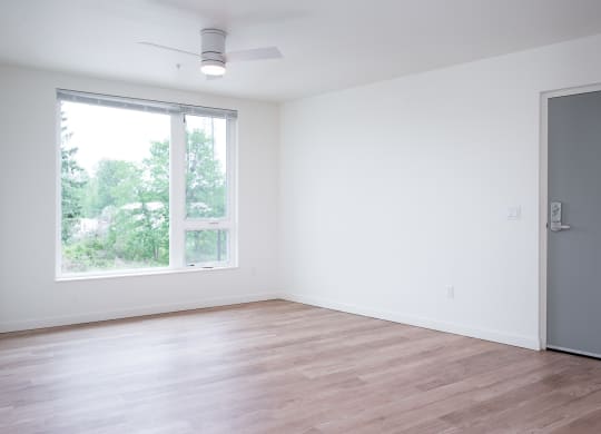 an empty room with a large window and wooden floors
