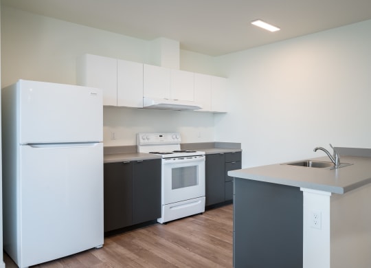 a kitchen with white appliances and gray countertops