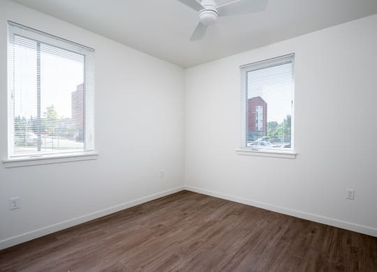 an empty room with wood floors and two windows