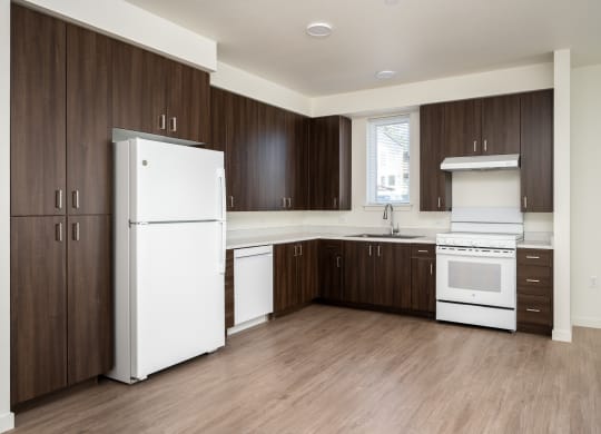 an empty kitchen with white appliances and wooden cabinets
