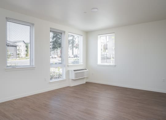 an empty living room with a wood floor and three windows