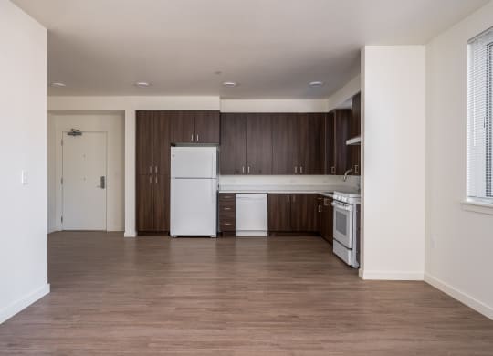 an empty kitchen with white appliances and wood flooring in an apartment