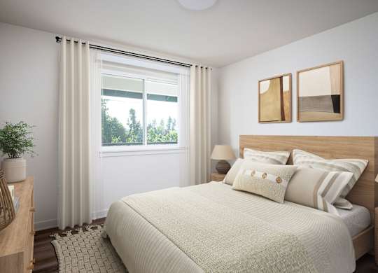 A bedroom with a large bed and a window with curtains.
