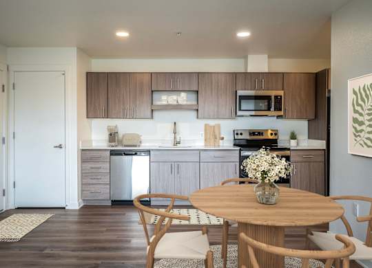 A kitchen with a table and chairs in the foreground and a white door in the background.