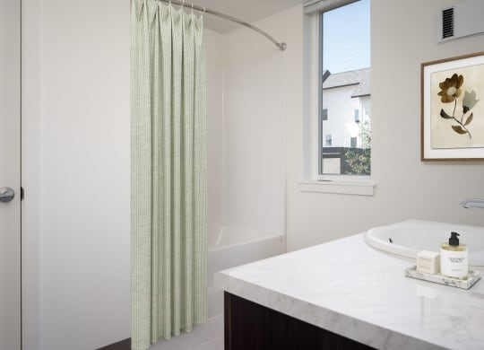 a bathroom with a shower and a sink and a window
