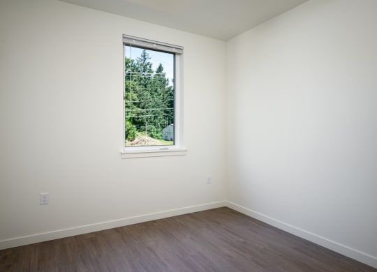 a white room with a window and wooden floors