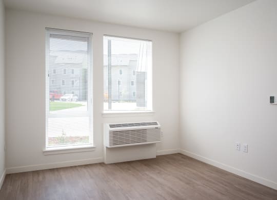an empty room with two windows and a heater in the corner