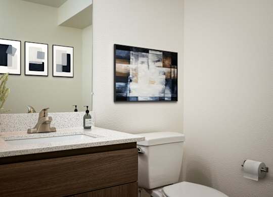 A bathroom with a toilet, sink, and a picture on the wall.