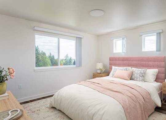 A bedroom with a large bed and a window overlooking trees.