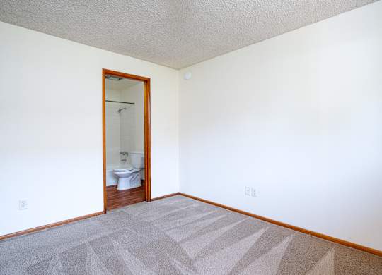 A bathroom with a toilet and a mirror is visible through the door.
