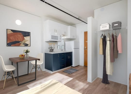 a small room with a desk and a kitchen in it