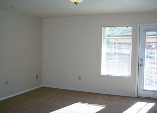 an empty living room with a door and window