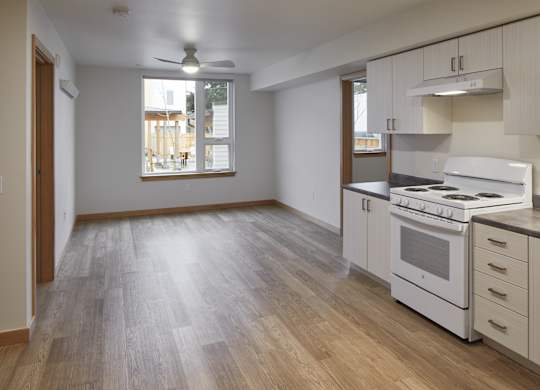 A kitchen with white appliances and wooden floors.