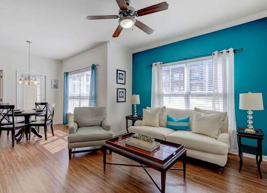 A living room with a white couch, a coffee table, and a dining table at Ethan Pointe Apartments, Greensboro, 27215