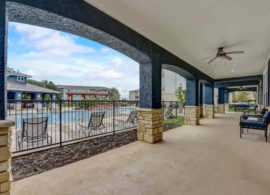 A patio with a pool and a black metal fence.