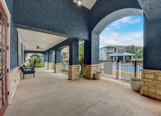 A patio area with a pool and a building in the background.