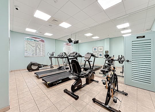 A gym with treadmills, exercise bikes, and a weight bench.