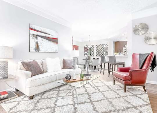 A living room with a white couch, a red chair, and a coffee table.