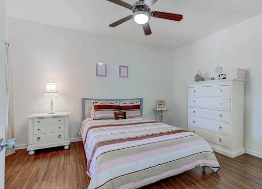 A bedroom with a bed, dresser, and ceiling fan at Ethan Pointe Apartments, North Carolina