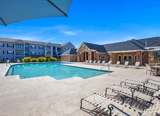 A large outdoor swimming pool surrounded by lounge chairs and umbrellas at Ethan Pointe Apartments, North Carolina