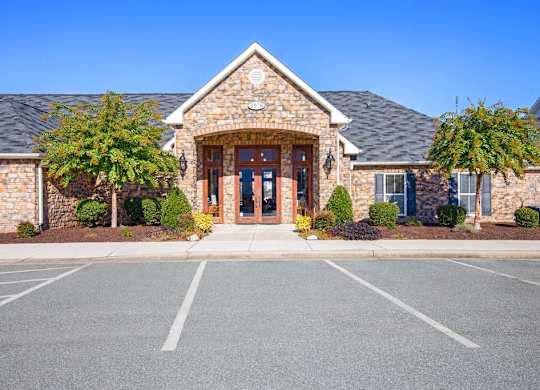 A building with a stone facade and a large front door is surrounded by a parking lot at Ethan Pointe Apartments, Greensboro, NC, 27215