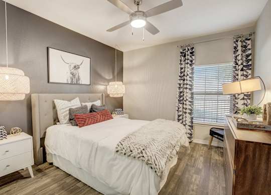 A bedroom with a bed, nightstand, and a ceiling fan.