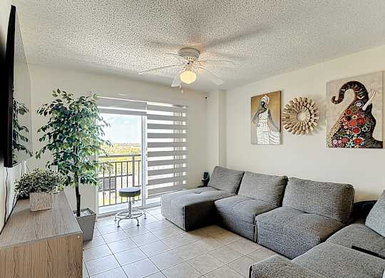 A living room with a grey couch and a ceiling fan.