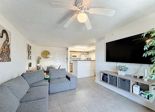 A living room with a grey sofa and a black TV on the wall.