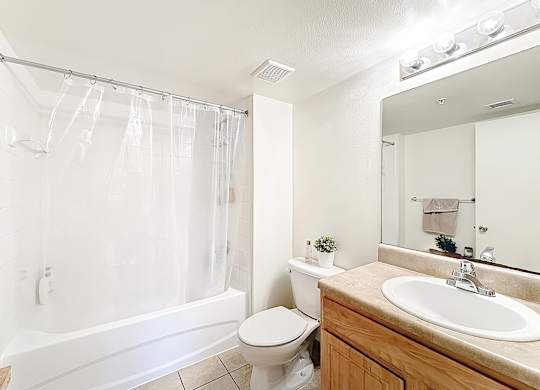 A white bathroom with a toilet, sink, and shower.
