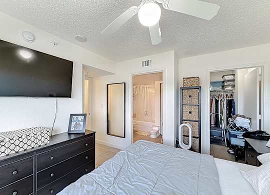 A bedroom with a bed, dresser, and a ceiling fan.