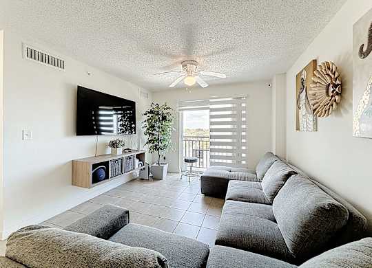 A living room with a grey couch and a ceiling fan.