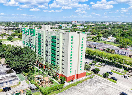 A tall green and white building stands in the middle of a parking lot.
