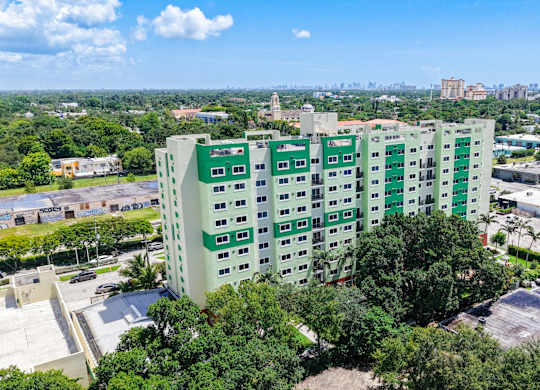 A green and white building with a parking lot in front.