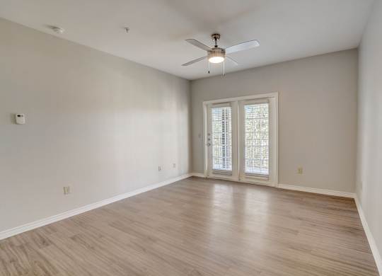 A room with a ceiling fan and a sliding glass door.