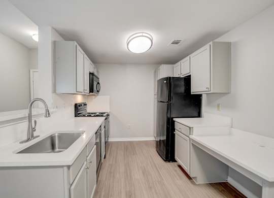 A kitchen with black appliances and wooden cabinets.