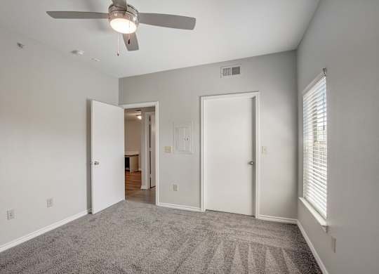 A room with a ceiling fan and carpeted floor.