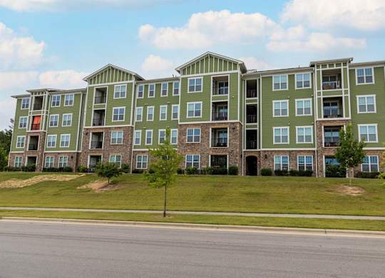 A large green apartment building with a tree in front at Foxwood Apartments, Raleigh-Durham
