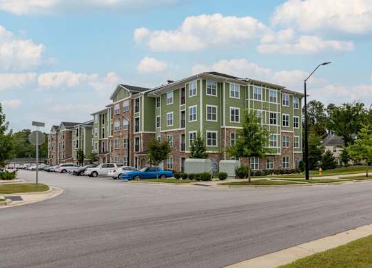 A street view of a residential area with apartment buildings and parked cars at Foxwood Apartments, Raleigh-Durham, NC