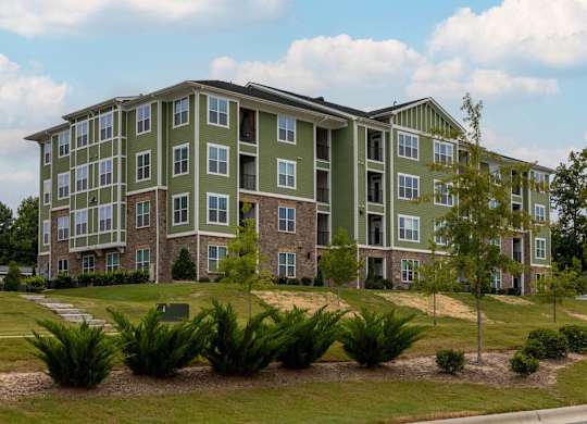 A large green apartment building with a grassy front yard at Foxwood Apartments, North Carolina
