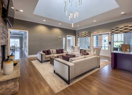 A modern living room with a stone fireplace and a large chandelier at Foxwood Apartments, Raleigh-Durham, 27616