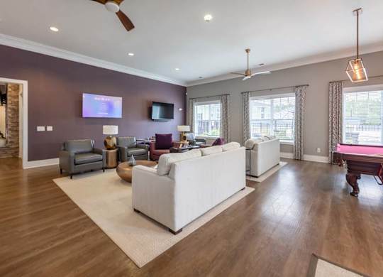A living room with a white couch and a television on the wall at Foxwood Apartments, Raleigh-Durham, NC