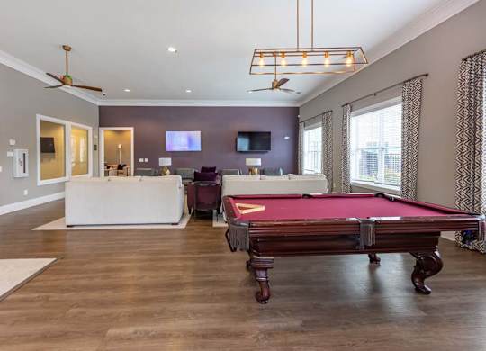 A pool table is in the middle of a room with a television and a couch at Foxwood Apartments, Raleigh-Durham